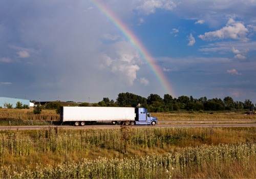 A truck driving with a rainbow in the background, working for Trucking Companies in Davenport IA