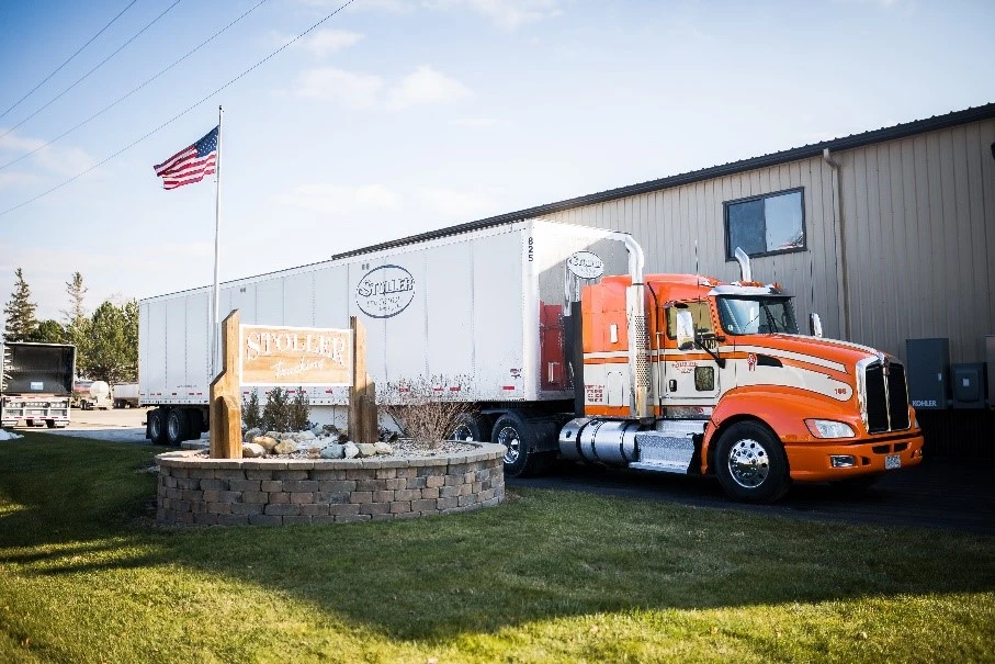A large orange truck outside of Stoller Trucking, ready for freight shipping in Iowa
