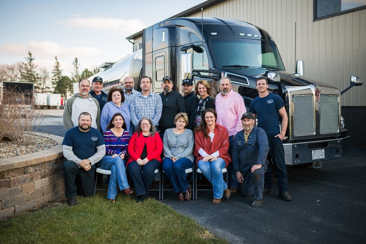 Group photo of the Stoller Trucking team standing in front of Illinois freight trucking vehicles and trailers.