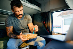 A man eats lunch in his semi after reading Tips for Healthier Eating on the Road
