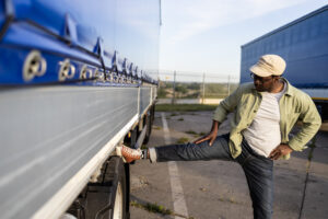 Expert Tips for Lower Back Pain Relief on the Road 2 Professional driver doing exercise and stretching his legs on parking lot. Follow these tips for lower back pain to stay healthy on the road.